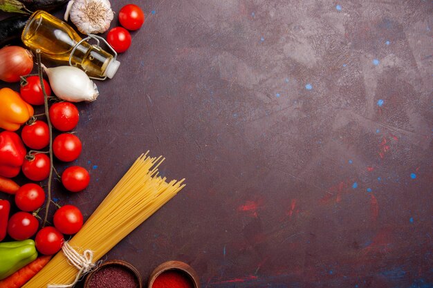 Vista dall'alto diverse verdure fresche con pasta italiana su uno spazio buio