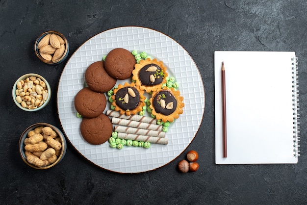 Vista dall'alto diversi biscotti al cioccolato con noci sui biscotti di torta dolce torta di zucchero di superficie grigio scuro