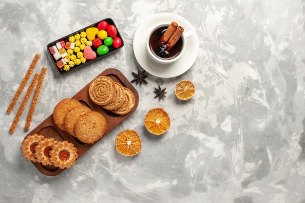 Vista dall'alto diversi biscotti con caramelle e tazza di tè su sfondo bianco biscotto biscotto zucchero cuocere torta torta dolce