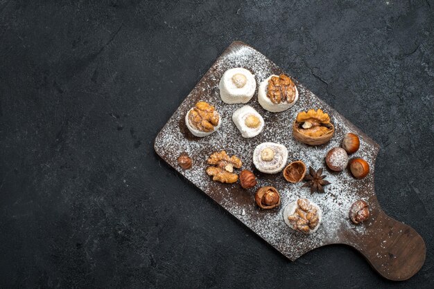 Vista dall'alto diversi biscotti con torte e noci sulla scrivania grigio scuro