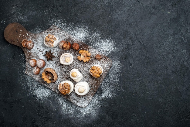 Vista dall'alto diversi biscotti con torte e noci sulla superficie grigio scuro