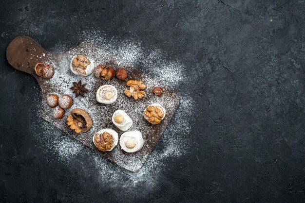 Vista dall'alto diversi biscotti con torte e noci sulla superficie grigio scuro