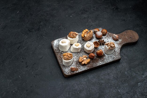 Vista dall'alto diversi biscotti con torte e noci sulla superficie grigio scuro