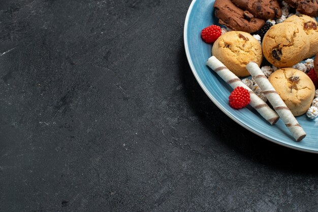 Vista dall'alto diversi biscotti dolci e deliziosi all'interno su una superficie grigio scuro