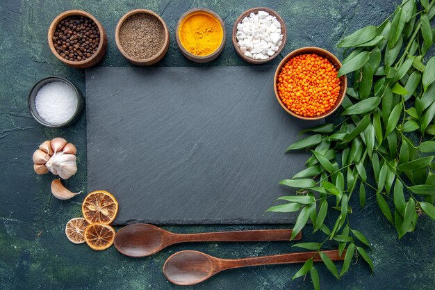 Vista dall'alto diversi condimenti con aglio e lenticchie arancioni su sfondo blu scuro foto cibo piccante peperoncino colore zuppa di semi taglienti
