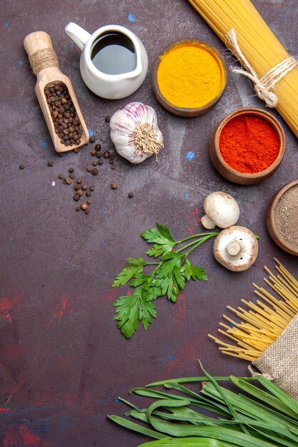 Vista dall'alto diversi condimenti con pasta cruda e funghi su una superficie scura pasto prodotto cibo crudo