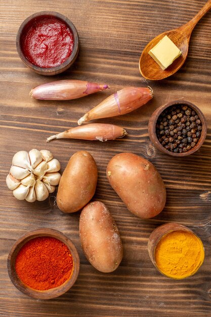Vista dall'alto diversi condimenti con patate e aglio su una scrivania in legno marrone piccante edgy pepper maturo