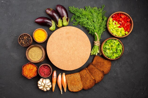 Vista dall'alto diversi condimenti con verdure e pagnotte di pane scuro su sfondo scuro condimenti per insalata pane cibo salutare