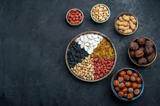 Vista dall'alto diversi dadi con uvetta e frutta secca sullo sfondo grigio scuro nocciola nocciola noce spuntino nocciola