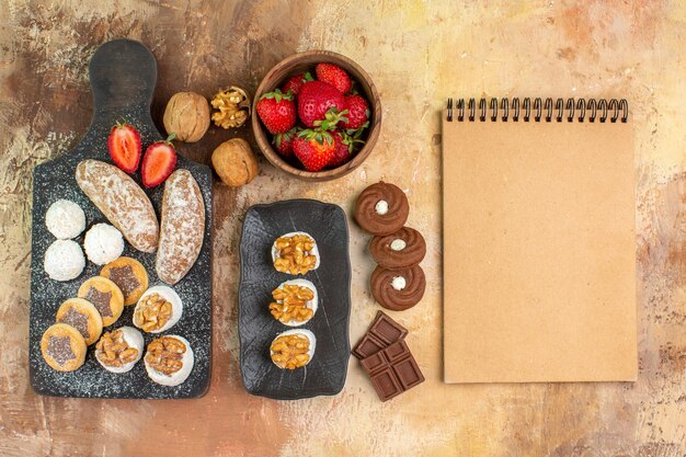 Vista dall'alto diversi dolci con biscotti e frutta sulla scrivania leggera