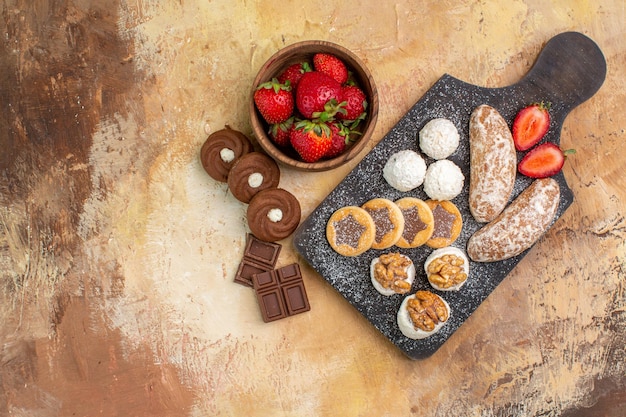 Vista dall'alto diversi dolci con biscotti e frutta sulla scrivania leggera
