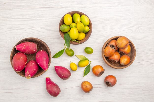 Vista dall'alto diversi frutti freschi all'interno di piatti su scrivania bianca frutta tropicale dieta matura colore esotico