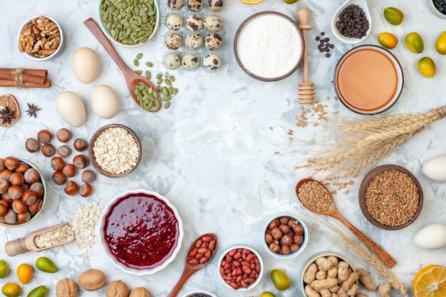 Vista dall'alto diversi ingredienti torta gelatina uova noci semi e farina su pasta bianca torta colorata biscotto dolce zucchero foto dado