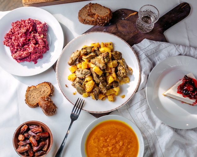 Vista dall'alto diversi pasti come zuppa di insalata di carne fritta e fetta di torta sul pavimento bianco