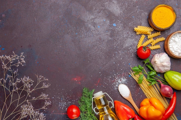 Vista dall'alto diversi prodotti pasta cruda diversi condimenti e verdure su sfondo scuro dieta salute cibo crudo