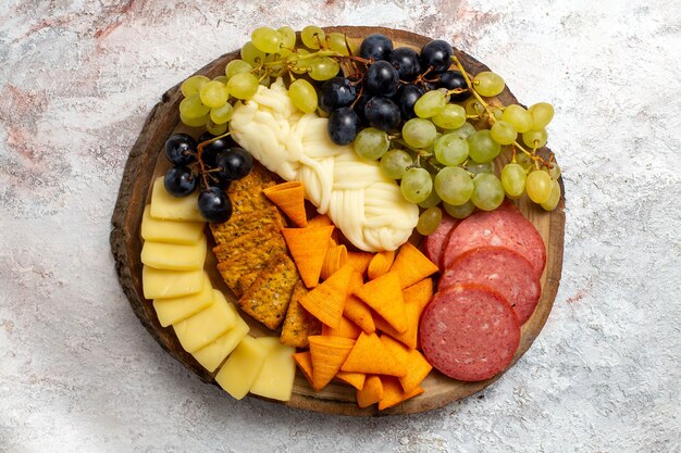 Vista dall'alto diversi snack cips salsicce formaggio e uva fresca su uno spazio bianco