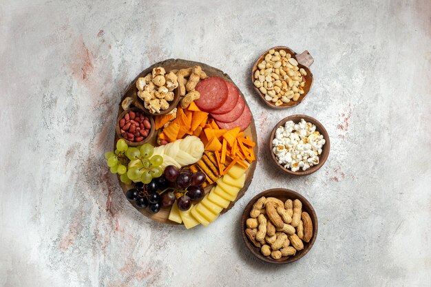 Vista dall'alto diversi snack noci cips formaggio e salsicce su sfondo bianco dado spuntino pasto cibo