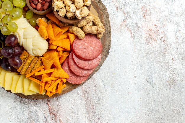 Vista dall'alto diversi snack noci cips formaggio e salsicce su sfondo bianco dado spuntino pasto cibo