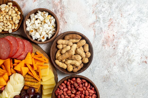 Vista dall'alto diversi snack noci cips formaggio e salsicce su sfondo bianco dado spuntino pasto cibo