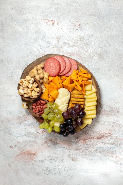 Vista dall'alto diversi snack noci cips uva formaggio e salsicce sulla superficie bianca dado spuntino pasto cibo frutta