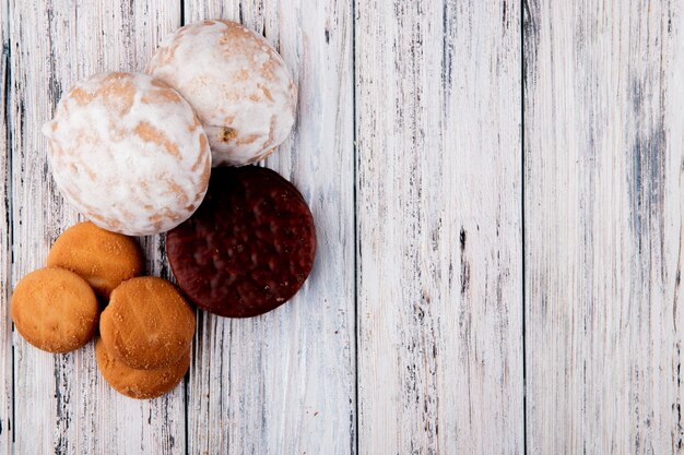 vista dall'alto Dolci biscotti alla vaniglia biscotti al cioccolato e pan di zenzero a sinistra con copia spazio su sfondo bianco in legno