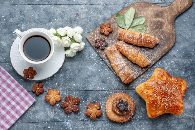 Vista dall'alto dolci deliziosi biscotti con una tazza di caffè e braccialetti dolci il caffè dolce zucchero grigio da scrivania