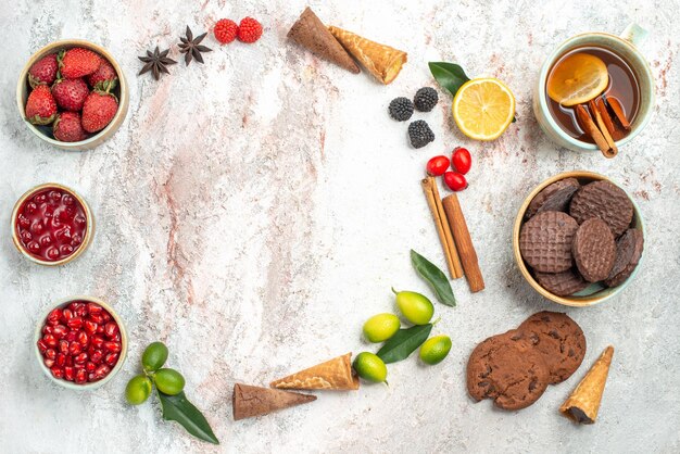 Vista dall'alto dolci una tazza di tè con biscotti al cioccolato alla cannella ciotole di marmellata di frutti di bosco agrumi