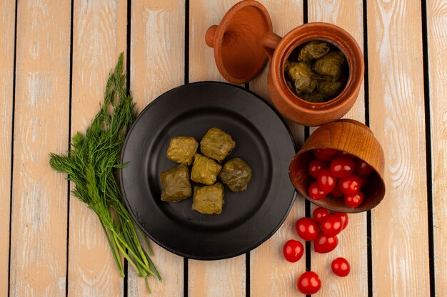 vista dall'alto dolma carne macinata all'interno della banda nera con verdure e pomodorini rossi sulla scrivania in legno