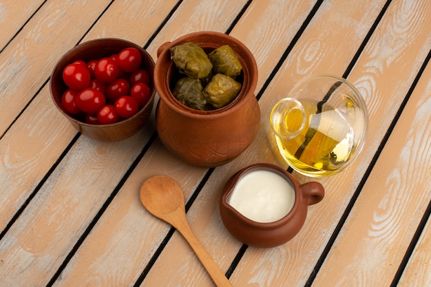 vista dall'alto dolma insieme a pomodori rossi olio d'oliva e yogurt sulla scrivania in legno rustico