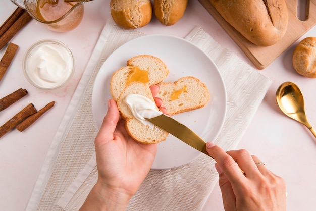 Vista dall'alto donna spalmando crema di formaggio sul pane