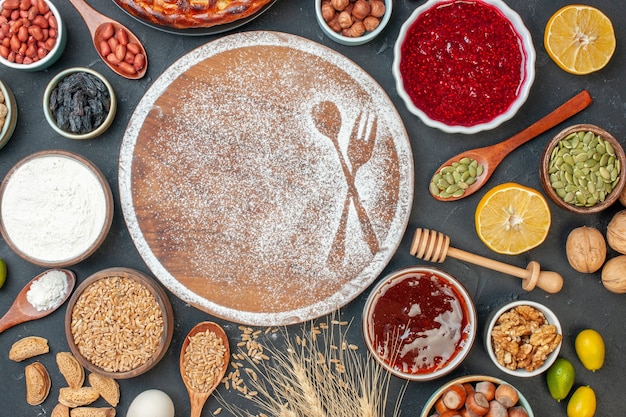 Vista dall'alto farina bianca a forma di forchetta e cucchiaio con uova e noci su torta scura dolce tè dolce biscotto pasticceria torta