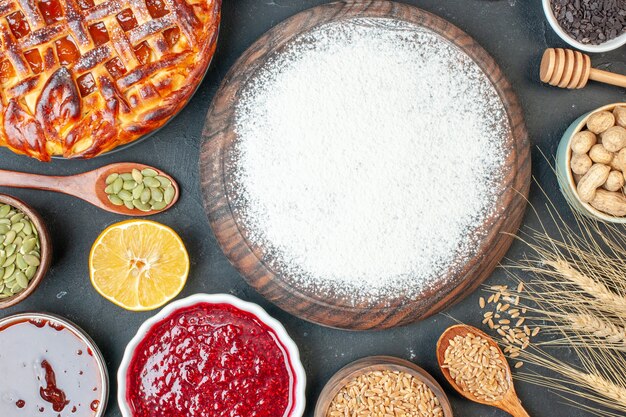 Vista dall'alto farina bianca con semi freschi e marmellata su una torta di frutta scura torta di zucchero torta di tè pasticceria dolce biscotto