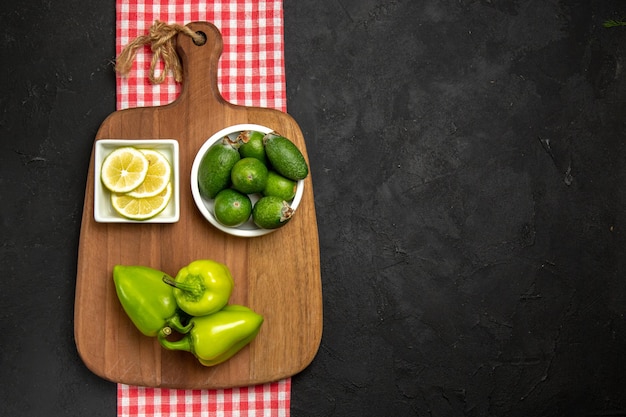 Vista dall'alto feijoa fresca con peperone verde e limone sulla superficie scura della farina di agrumi di frutta