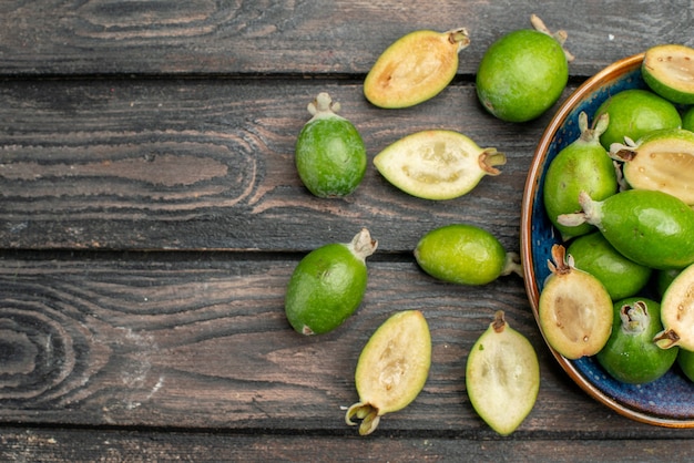 Vista dall'alto feijoas verdi freschi all'interno del piatto su scrivania in legno rustico frutta colore foto succo maturo acido spazio libero