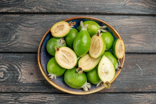 Vista dall'alto feijoas verdi freschi all'interno del piatto su scrivania in legno rustico frutta colore foto succo maturo acido