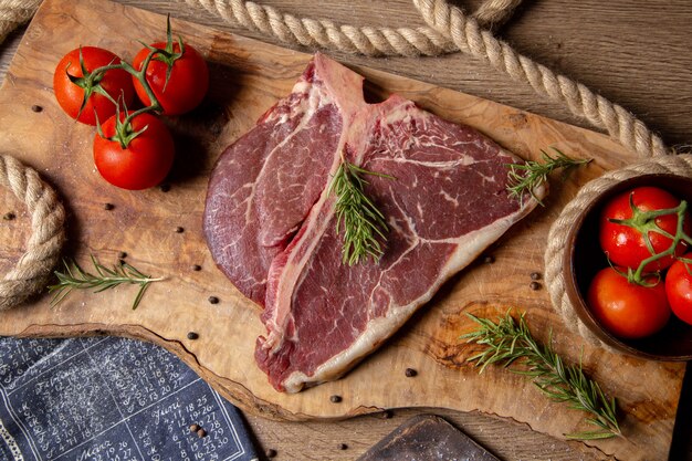 Vista dall'alto fetta di carne cruda con pomodori rossi freschi verdi sul pasto di legno sfondo cibo crudo