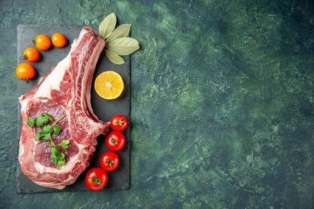 Vista dall'alto fetta di carne fresca con pomodori su sfondo blu scuro cibo carne cucina animale mucca macellaio pollo colore spazio libero