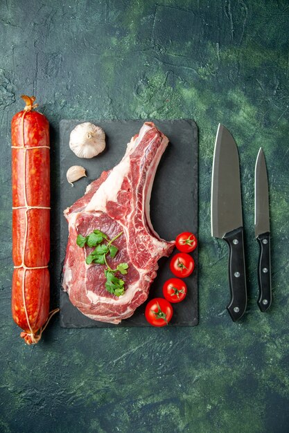 Vista dall'alto fetta di carne fresca con salsiccia su sfondo blu scuro carne cucina animale mucca cibo macellaio pollo colore