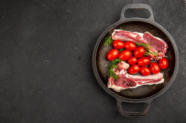 Vista dall'alto fette di carne con pomodori rossi all'interno della padella su sfondo grigio pollo crudo mucca pepe colore carne foto animali