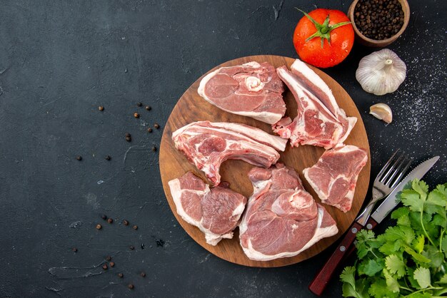 Vista dall'alto fette di carne fresca carne cruda con verdure e pomodori su cibo da cucina scuro cibo per mucche piatto per insalata animale
