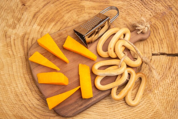 Vista dall'alto fette di formaggio grattugia bagel ovali su tagliere su fondo di legno