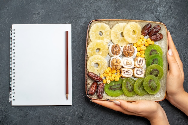 Vista dall'alto fette di frutta secca anelli di ananas e kiwi con noci sulla scrivania grigia frutta secca uva passa dolce vitamina salute