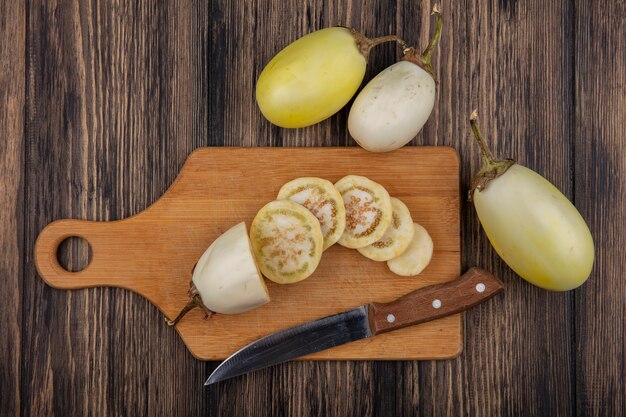 Vista dall'alto fette di melanzane bianche con coltello sul tagliere su fondo di legno