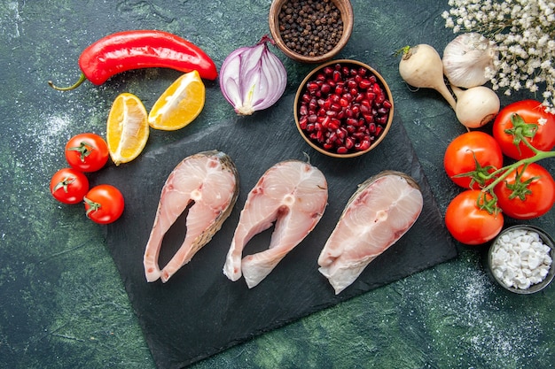 Vista dall'alto fette di pesce fresco con pomodori rossi sulla tavola scura frutti di mare oceano carne farina di mare pepe piatto cibo insalata acqua