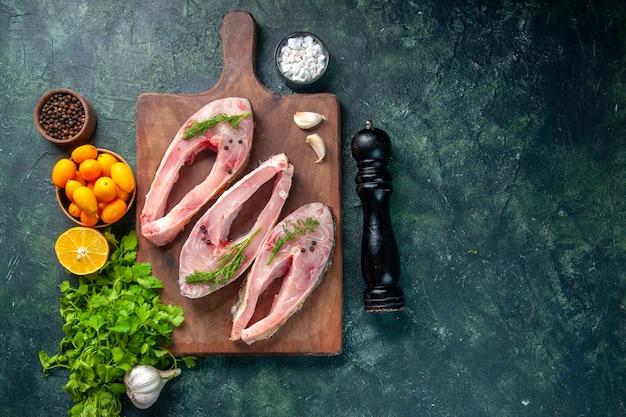 vista dall'alto fette di pesce fresco con verdure e kumquat su sfondo scuro