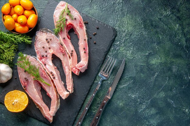 vista dall'alto fette di pesce fresco con verdure e kumquat su sfondo scuro