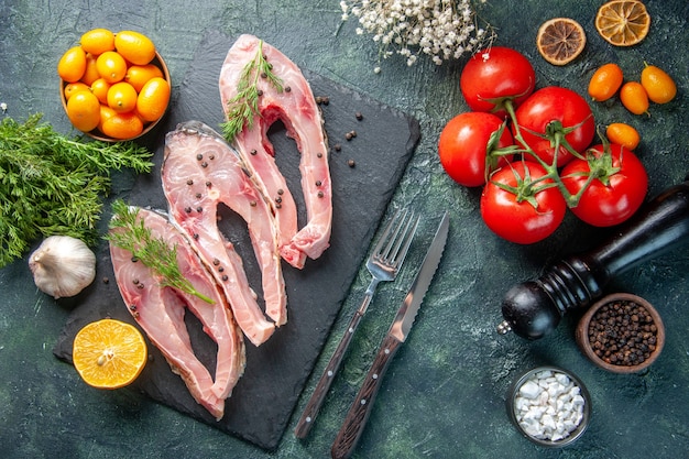 vista dall'alto fette di pesce fresco con verdure e kumquat su sfondo scuro