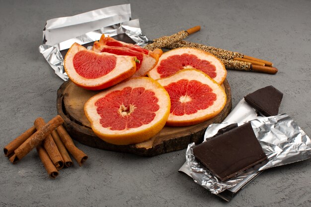 vista dall'alto fette di pompelmi lungo cannella e barrette di cioccolato sullo sfondo grigio