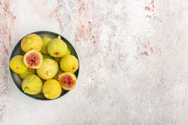 Vista dall'alto fichi freschi feti dolci all'interno del piatto sulla superficie bianca