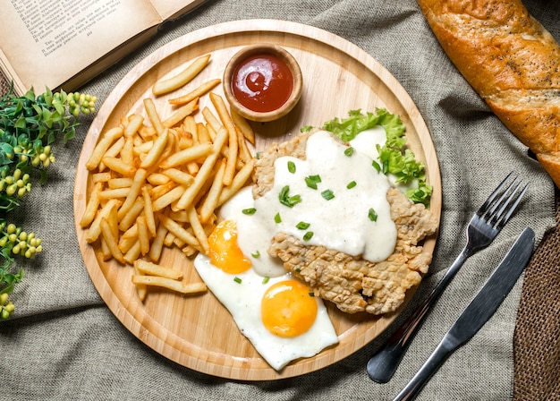 Vista dall'alto filetto di pollo alla griglia con salsa di uova fritte ketchup di lattuga e patatine fritte su una tavola